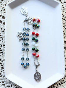 Both the blue and red and green novena chaplets are on a white tray with a lace background. 