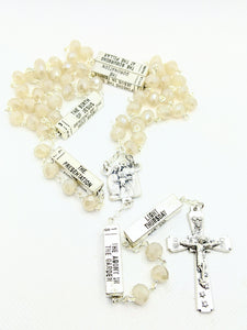 A pearl glass bead mysteries rosary lays on a white background
