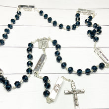 Load image into Gallery viewer, A deep blue mysteries rosary lays on a white washed wooden background