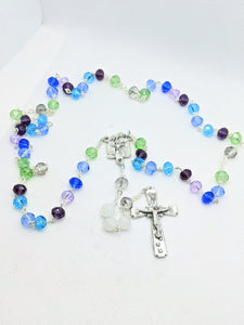 A family birthstone rosary features multiple colors to show each family members birth stone. It lays on a white background. 