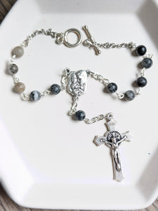 A close up of the jasper car rosary on a whote tray background