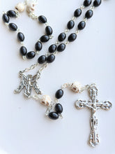 Load image into Gallery viewer, A close up of the black oval wooden shaped bead rosary with skull shaped oir father beads, an ornage M shaped centerpiece for Mary and a skull engraved crucifix