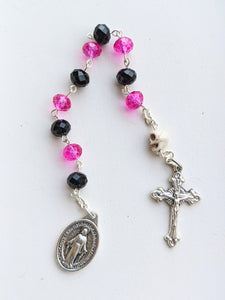 A closeup of the black and pink with skull 10 bead pocket rosary