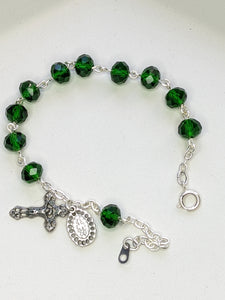A close up of a dark emerald green rosary bracelet on a white background
