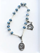 Load image into Gallery viewer, a blue crystal glass bead St Andrew chaplet sits on a plain white background with a St Andrew medal and a Nativity charm tracker on a lobster clasp to help keep your place during the daily novena