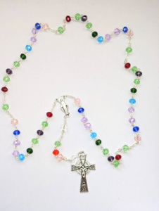 A family birthstone rosary features multiple colors to show each family members birth stone. It lays on a white background. 