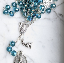 Load image into Gallery viewer, A teal 7 sorrows chaplet with a small pelican charm lays on a marble background 